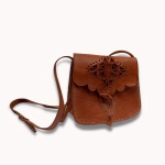 Brown leather shoulder bag styled with evening wear in candlelit setting