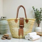 Leather straw tote on spa counter with towels, braided leather handles and wooden toggle