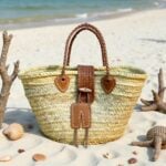 Leather straw tote on beach sand with seashells and braided leather handles