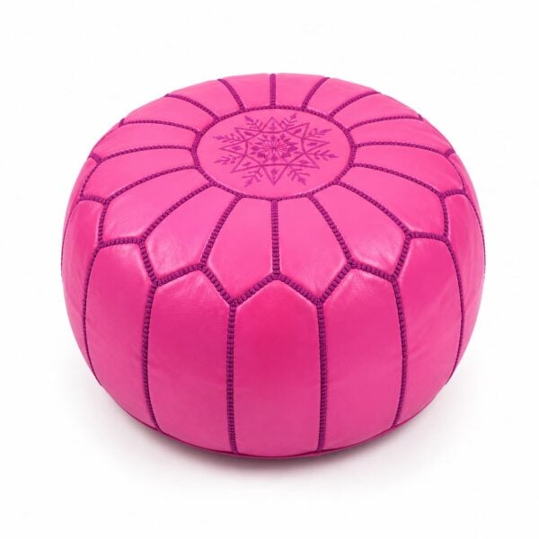 Vibrant pink leather round ottoman featuring traditional handcrafted patchwork goatskin and intricate embroidery on a white background.