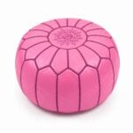 Vibrant pink leather round ottoman featuring traditional handcrafted patchwork goatskin and intricate embroidery on a white background.