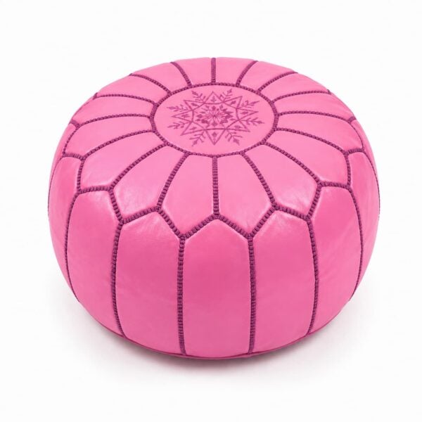 Vibrant pink leather round ottoman featuring traditional handcrafted patchwork goatskin and intricate embroidery on a white background.