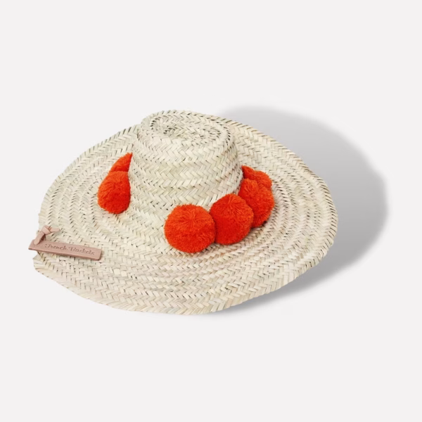 Red pompom-adorned handcrafted straw beach hat