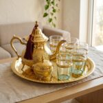 A steaming hot brass tea set 9-piece with sugar bowl resting on a beige linen table runner in a well-lit, cozy home living room setting.