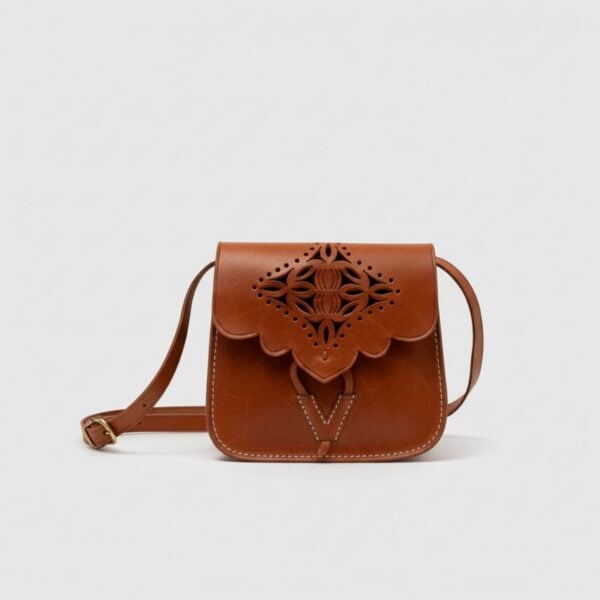Brown leather shoulder bag with embossed floral cutwork design and adjustable strap on white background
