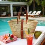 Palm leaf belted straw bag with leather buckle closure poolside beside tropical drink and coconut