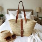 Handwoven palm leaf belted straw bag with leather buckle and cross-stitched straps on white bedding