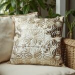 Set of leather pillow covers with floral cutwork on wicker chair with houseplants in coastal boho setting