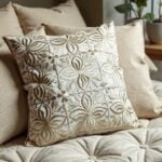 Leather pillow covers set in beige featuring floral cutwork displayed on beige couch near sunny window with plants