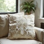 Leather pillow covers in beige with dimensional floral cutwork arranged on armchair in bright natural light
