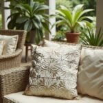Beige leather pillow cover with floral cutwork detail displayed on neutral sofa with tufted upholstery texture