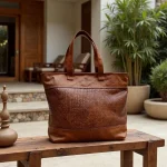 Handwoven leather tote bag with basketweave center on marble table with scenic view
