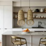 Handwoven straw lighting pair above marble kitchen island with modern minimalist cabinetry