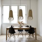 Handwoven straw lighting trio above dining table with black chairs near bright window