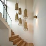 Handwoven straw lighting cluster in stairwell with natural cylindrical palm leaf shades and frayed edges