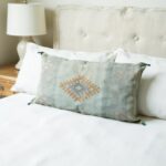 Handwoven cactus silk pillow 36 inch sage green lumbar cover with corner tassels on white tufted bed