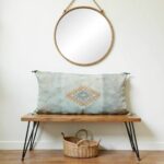 Handwoven cactus silk pillow 36 inch sage green lumbar cover on wooden bench beneath round mirror