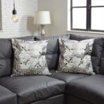 Gray floral pillow covers on dark leather sectional sofa in contemporary living room