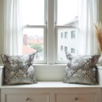 Gray floral pillow covers on window seat with natural light highlighting embroidered details