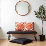 Orange embroidered cotton cushion set on dark sofa with exposed brick, industrial pendant lighting