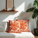 Orange medallion embroidered cotton cushion covers on beige sofa with monstera plant and wooden shelves