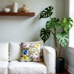 Single embroidered pillow cover on cream loveseat highlighting dimensional floral garden design craftsmanship