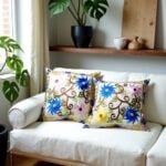 Pair of embroidered pillow covers on neutral sofa with dimensional floral embroidery and vine patterns