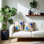 Two embroidered pillow covers on white sofa with blue yellow purple flowers and green vine embroidery detail