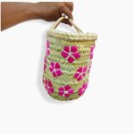 Small straw bag hand-held pink floral cylindrical basket with woven handle showing compact size