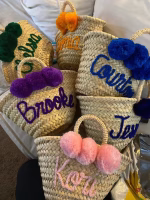 Personalized straw bags with blue names and coordinating pom poms