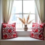 Red embroidered pillow covers styled on window seat with neutral curtains, showcasing dimensional floral appliqué detail