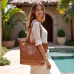 Side view of model with tan leather shopper bag in courtyard