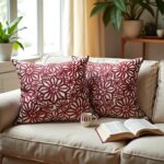 Red floral pillow covers on beige sofa near window, handcrafted burgundy flower cushions with plants decor