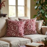 Red floral pillow covers on cream couch, burgundy appliqué cushions in natural light home interior setting