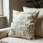Close-up of beige leather pillow cover showing detailed floral cutwork appliqué and dimensional petal design