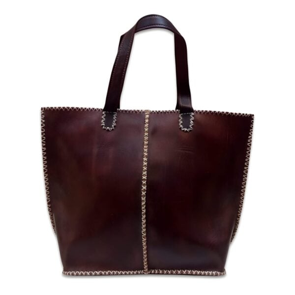 Dark brown leather tote bag with cream zigzag stitching and reinforced handles on white background