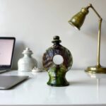 Round ceramic candle 11.8" green glazed holder displayed on modern white desk with brass lamp accent