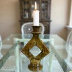 Geometric ceramic candle holder in Tamegroute green glaze centered on glass coffee table in living room