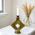 Tamegroute green ceramic candle holder with diamond cutout on white marble table beside dried wheat vase