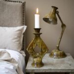 Handcrafted ceramic candle holder with diamond design in green glaze on bedside table with white candle