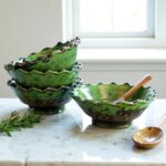 Handcrafted Tamegroute ceramic bowls stacked with wooden spoon on marble counter near window