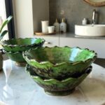 Green Tamegroute ceramic bowls with organic ruffled edges displayed on marble bathroom counter