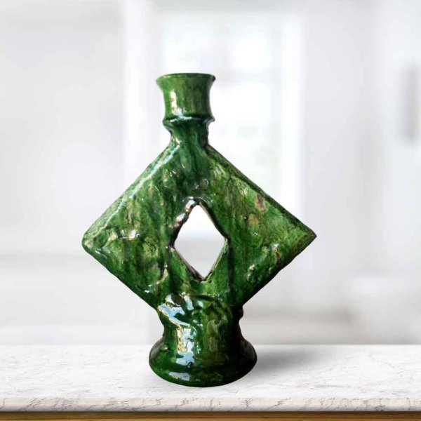 Close-up of handmade ceramic candle holder showcasing rich green glaze and unique diamond cutout design