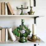 Vintage ceramic candle holder with grape vine relief displayed on white shelf with books