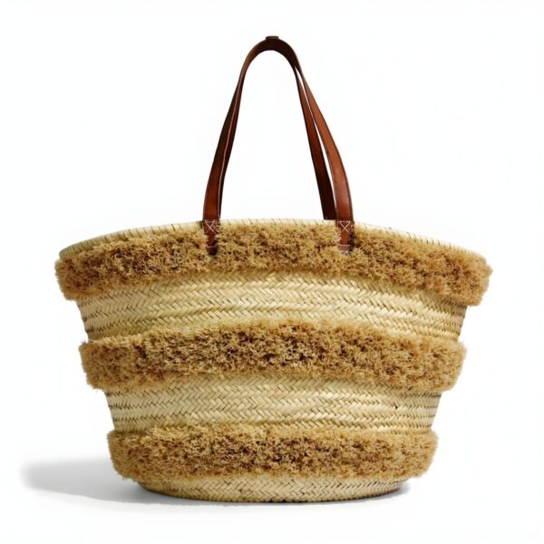 Close-up of woven straw texture and fuzzy fringe detail on striped bag.