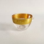 Glass coffee cup with amber-gold interior pattern and clear handle viewed from above on white surface