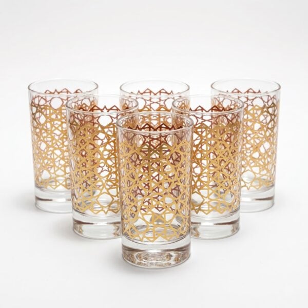 Set of six gold Moroccan tea glasses featuring a traditional geometric star pattern on clear glass, arranged against a seamless white background.