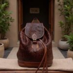 Brown woven leather backpack rucksack on neutral mat showing brass buckle and drawstring closure