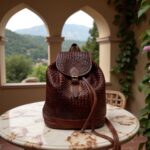 Handcrafted woven leather backpack in cognac brown on doormat showing intricate basketweave detail