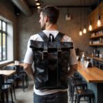 Man wearing black leather backpack with adjustable straps in modern cafe setting